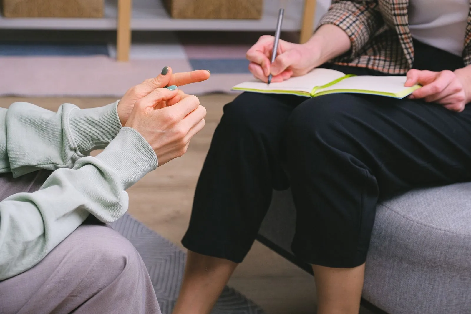Two people sit face to face across a small table, one explaining coverage details with hands and a notebook, the other listening.